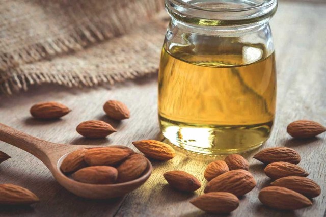 jar of almond oil, almond nuts and a spoon